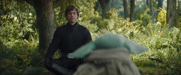 An image of a young Luke Skywalker showing Grogu how to meditate and channel the Force